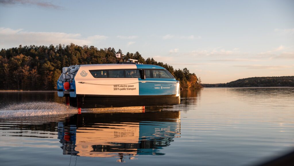 Candela P-12 electric ferry - hydrofoils across still lake with bushy island in background